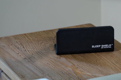 Phone under The Sleep Shield EMF-blocking cover beside bed